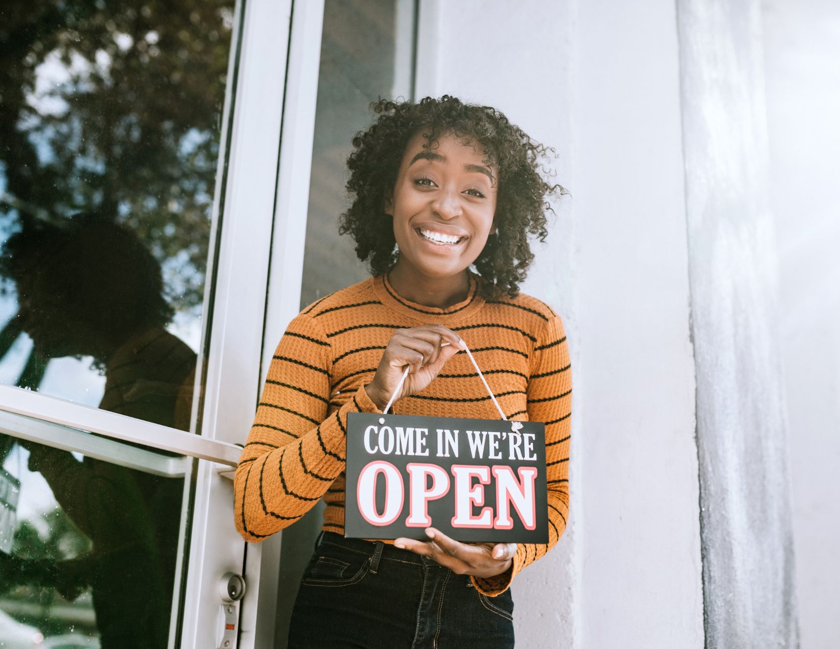 Young BIPOC woman with open sign for new business
